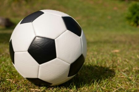 A black and white football resting on grass